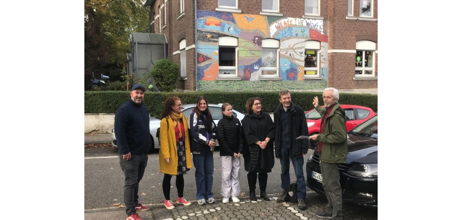 Foto vom Mosaik mit v.l.n.r.: Jugendpfleger Matthias Michels, Künstlerin Kerstin Thelen, Ferienspiele-Betreuerin Antonia Gilles, Kinderbürgermeisterin Zoe Kißling, Beigeordnete Renate Wallraff, Pastoralteam-Mitglied Bernhard Ruhl und Gemeindereferent Wilfried Hammers.